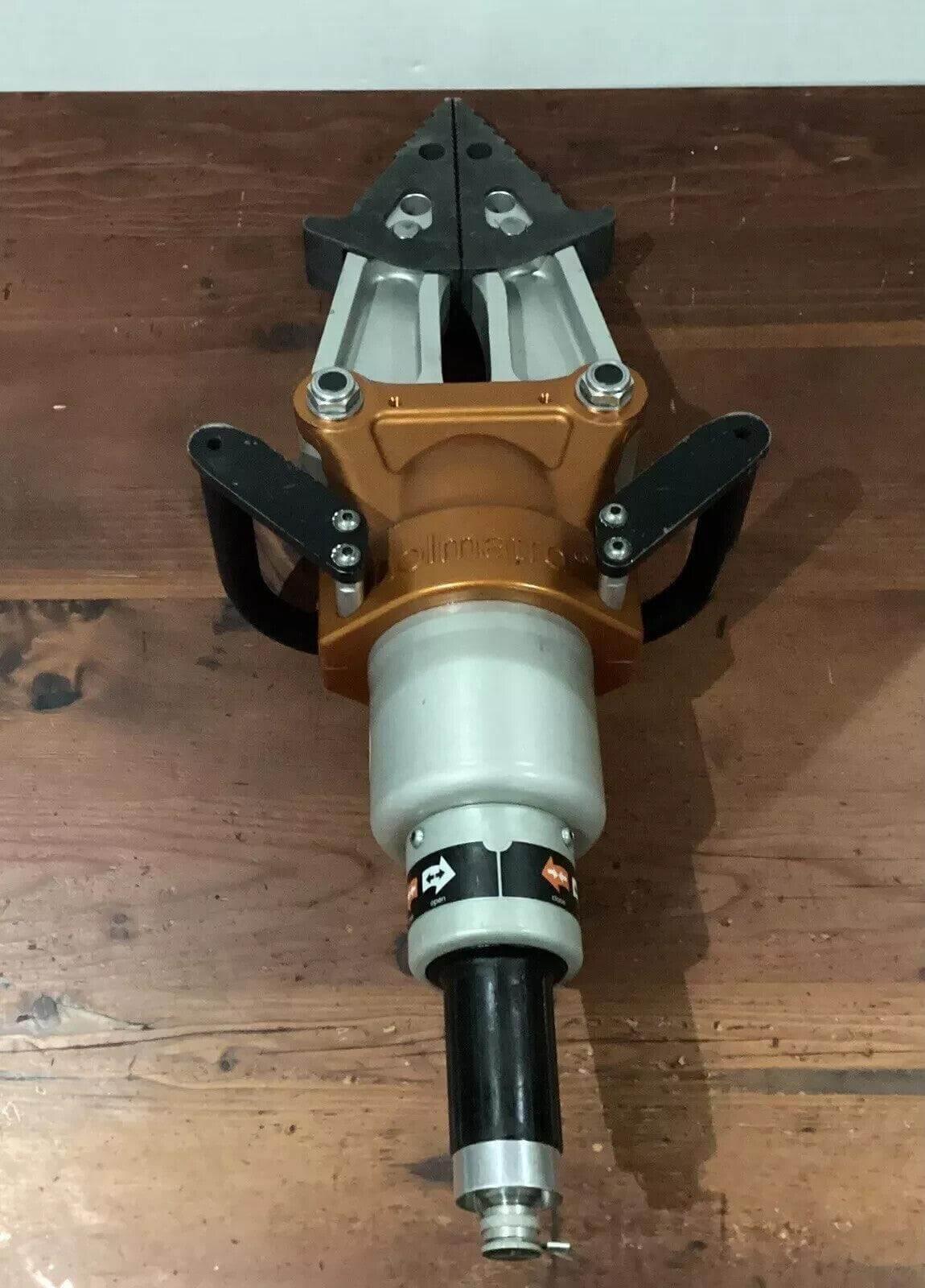 Hydraulic rescue tool with orange and black design, placed on wooden surface