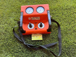 Orange Holmatro hydraulic control unit with dual gauges and joysticks on grass