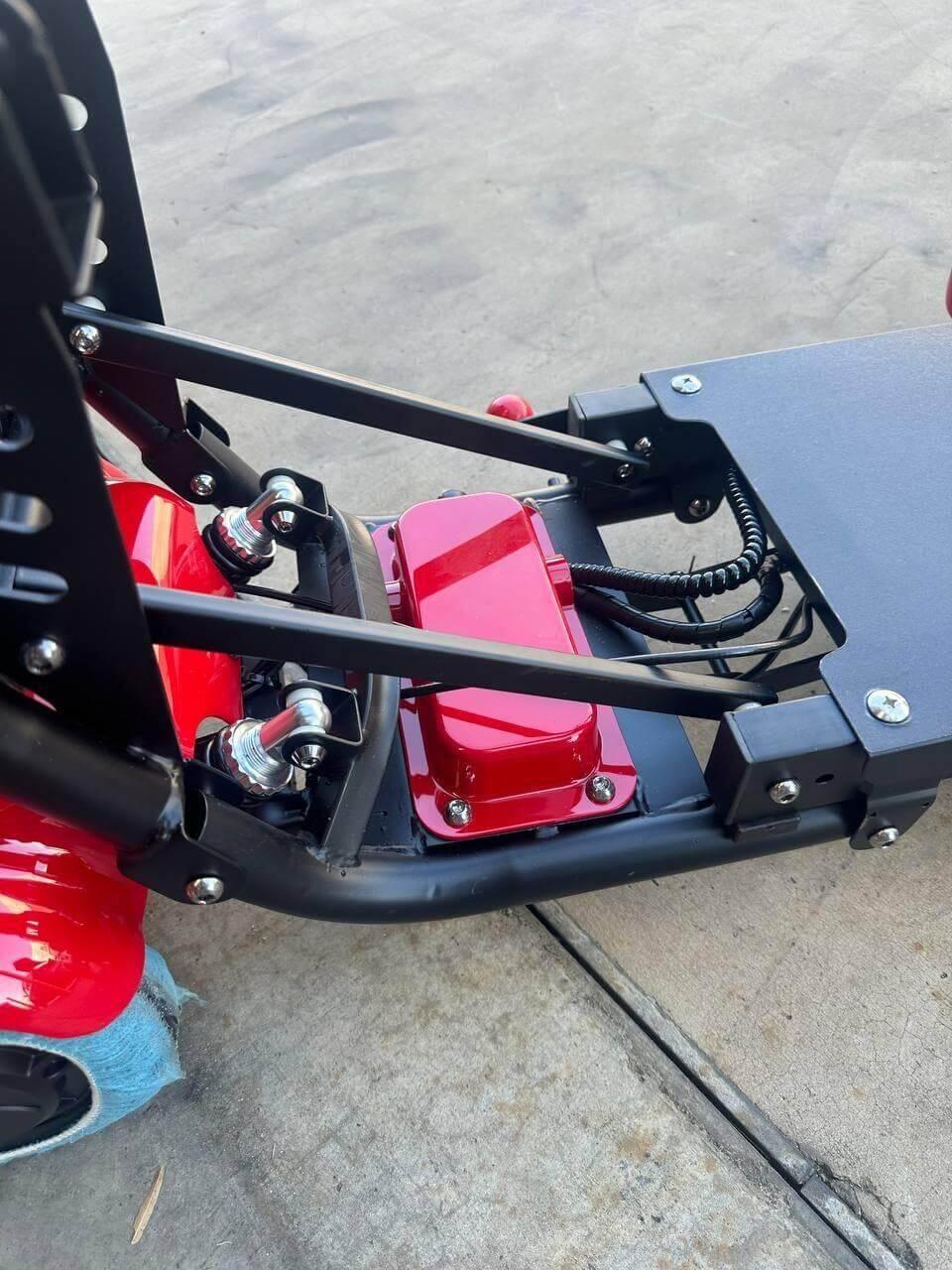 Red tractor part with black metal frame and wiring, showcasing durable construction for farm equipment.