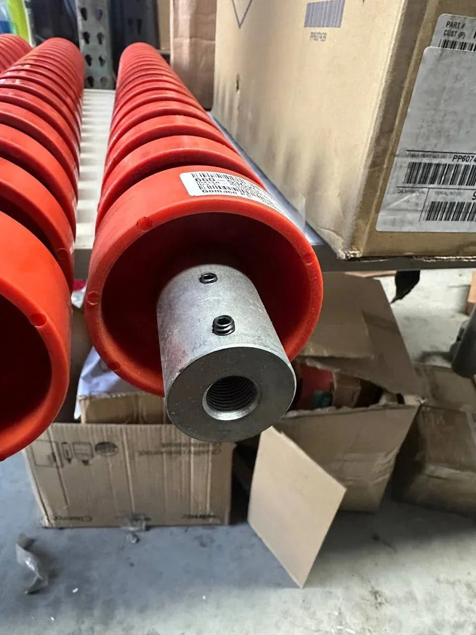 Red tractor parts with metal fittings, stored in warehouse boxes