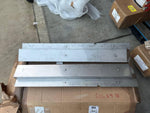 Metal tractor parts or industrial components stacked on cardboard boxes in warehouse setting