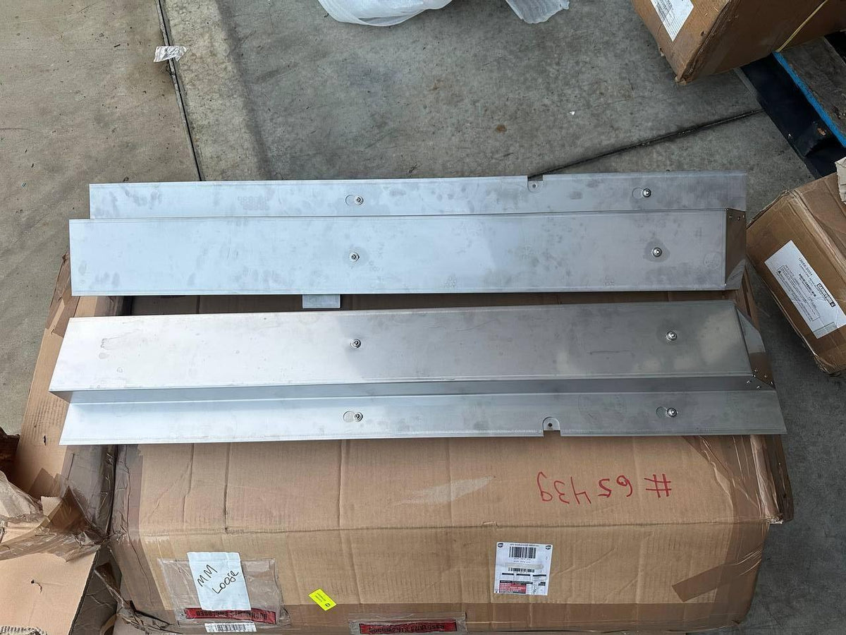 Metal tractor parts, industrial components for AGCO or EATON equipment, stacked on shipping box in warehouse