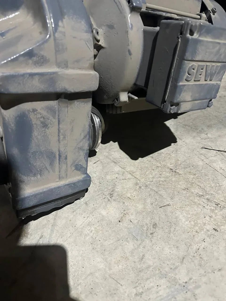 Dusty industrial SEW motor component on concrete floor, ideal for tractor or truck parts