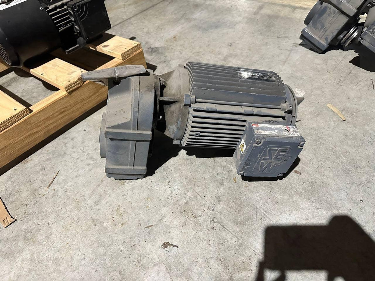 Industrial SEW motor with ribbed casing, placed on concrete floor near wooden pallets
