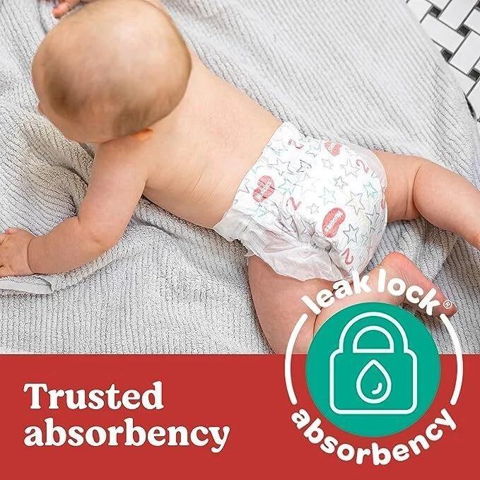 Baby wearing patterned diaper with leak lock absorbency feature on soft blanket