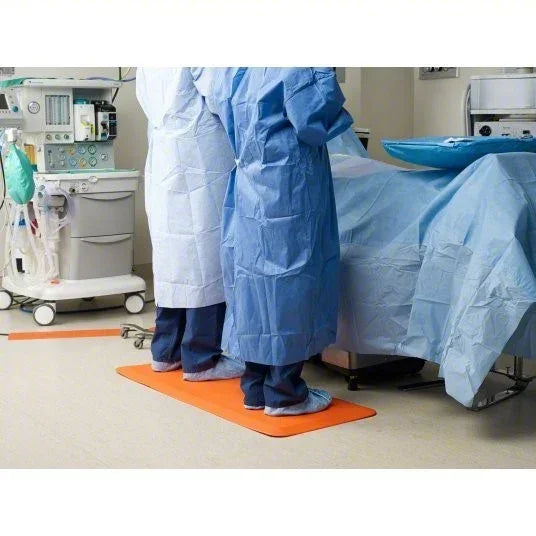 Medical staff in blue and white gowns standing on orange mat in hospital setting