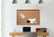 Wooden desk with corkboard, laptop, and office supplies in a bright workspace