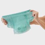 Mint green disposable adult diaper with star pattern, held in hands against white background