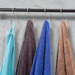 Four colorful microfiber towels hanging on S-hooks from a black rod, ideal for kitchen or workshop use.
