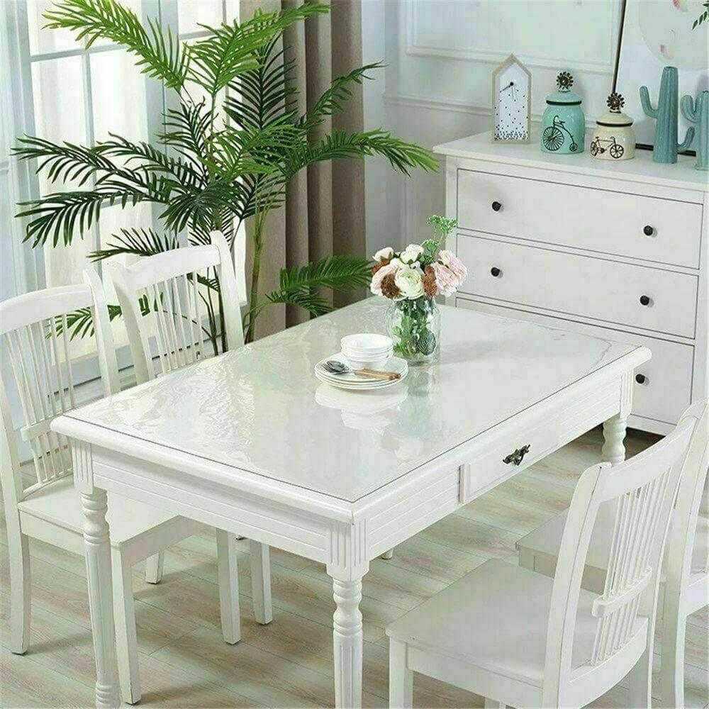 Clear PVC tablecloth plastic table cover on white dining table with chairs in bright room