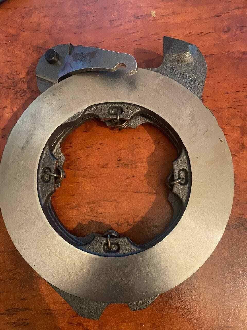 Tractor brake actuator metal component on wood surface, replacement tractor part