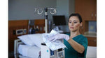 Nurse cleaning medical equipment in hospital room with disposable microfiber cloth