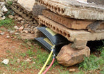 Black tractor tire under concrete blocks with yellow and red hoses connected outdoors