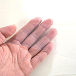 Hand holding a thin, clear PVC table cover, showcasing its lightweight and transparent design for table protection.