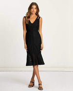Woman wearing a black lace midi dress with double shoulder straps, v-neck, and ruffled hem
