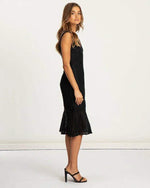 Woman wearing black lace midi dress with sleeveless design and flared hem, formal style