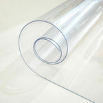 Rolled clear PVC tablecloth cover protector, durable and waterproof for dining tables.