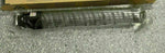 Black toner cartridge in protective plastic wrap on speckled floor, cardboard box behind