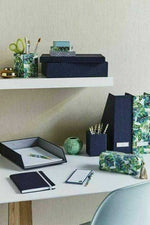 Modern office desk with tropical-patterned stationery, notebooks, pen holder, and storage boxes.
