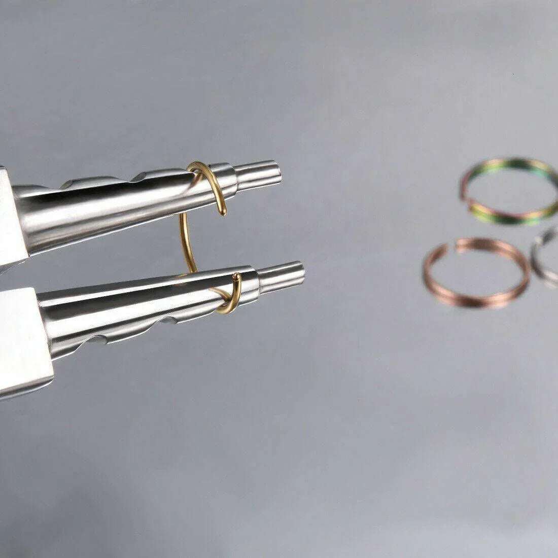 Assorted unisex fake nose rings in silver, gold and black, displayed with jewelry pliers