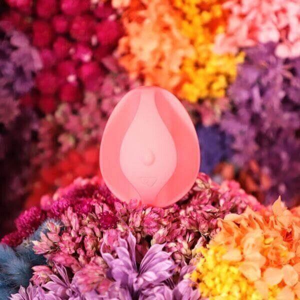 Pink silicone menstrual cup nestled in colorful dried flowers, eco-friendly period care product
