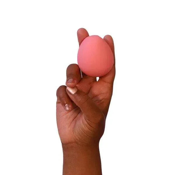 Pink makeup sponge held in hand, soft cosmetic applicator for blending foundation or powder